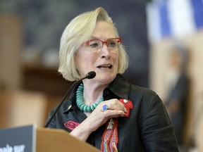 Indigenous Affairs Minister Carolyn Bennett touches a red dress pin symbolizing murdered and missing Indigenous women, as she speaks at the announcement of the inquiry into Murdered and Missing Indigenous Women on Aug. 3.