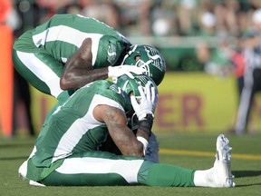 Jonathan Newsome, top, of the Saskatchewan Roughriders consoles defensive back Ed Gainey after a near-interception Saturday night at Mosaic Stadium.