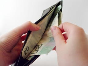 Woman pulling money out of a wallet. Getty Images/iStockphoto