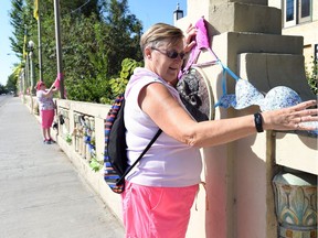 Erica Marwick (L) and Carol Marwick (R) both volunteers with the Canadian Breast Cancer Foundation, CIBC Run for the Cure adjust bras on the Albert Street bridge to bring attention to the upcoming run on Sunday, Oct. 2.