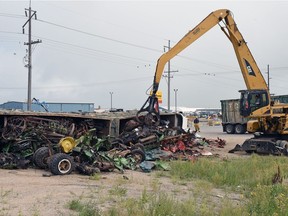 An operator uses an excavator with a claw to remove salvage metal scrap after a dual-trailer semi overturned at Armour Road and Highway 6.