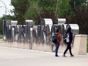 University of Regina students walk by the campus sign.