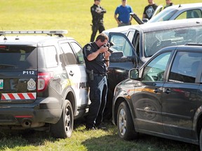 A member of the Brandon Police Service Forensic Identification Unit takes photos at the scene of a high-risk takedown in a field south of Kirkcaldy Drive after a police chase. Three suspects were taken into custody including a male adult, a female adult and a fifteen-year-old male youth. (Tim Smith/The Brandon Sun)