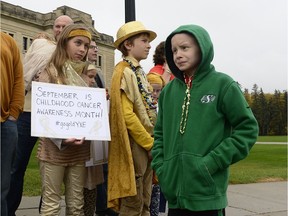 Moriah Anderson, left, holds a sign while brother Micah, center, and Joel Bachman, right, looks on at a flag raising ceremony in recognition of Childhood Cancer Awareness Month at the Legislative Building in Regina, Sask. on Saturday Sept. 24, 2016.