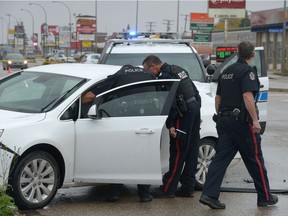 Regina Police Service members attend to a white car that was shot at on Victoria Ave. and MacKay St. in Regina, Sask. on Saturday Sept. 24, 2016. Unconfirmed reports suggested there were three shots fired. One bullet hole appears to have entered the driver's side window. MICHAEL BELL