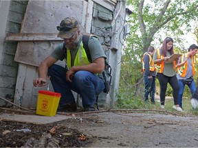 Spurgeon Root, left, picks-up a used needle for disposal while other volunteers from White Pony Lodge, a street patrol group, look for other like items at the back of an abandoned property in the 1200 Block of Retallack St. in North Central neighbourhood in Regina, Sask. on Saturday Sept. 3, 2016. MICHAEL BELL