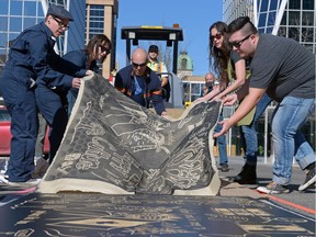 Members and supporters of Articulate Ink peel off a linen sheet that was pressed into an ink-covered woodcut by a Dynapac Roller on Scarth Street in downtown Regina on Sunday Oct. 2, 2016. The activity was part of Culture Days, a movement to increase the public's engagement with arts and culture in the community.