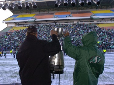 Long time Rider players Eddie Davis (in green) and Gene Makowsky walk with the Grey Cup as The Saskatchewan Roughriders made their first stop upon returning to Regina at Mosaic Stadium to a crowd of nearly 8,000 fans who braved -42 degree temperatures with the wind chill to greet their beloved Grey Cup Champions.
