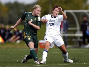 REGINA, SASK - Sept. 14, 2014  -  Mount Royal Cougars forward Hailey Lafave (#25) winces after Cougars midfielder Kayla McDonald (#3) fires the ball toward the goal during a game held at the university in Regina on Sunday Sept. 14, 2014. (