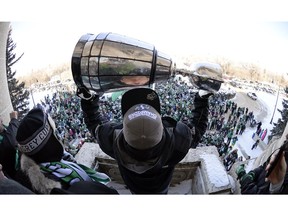 Saskatchewan Roughriders fullback Neal Hughes hoists the Grey Cup on the balcony of the Premier's office at the Saskatchewan Legislative Building on Nov. 26, 2013.