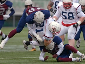 Two Regina Thunder defenders team up to tackle Calgary Colts running back Dylan Minshull during Sunday's PFC game at Mosaic Stadium.