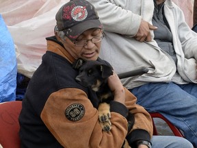 Occupants of the tent city in Regina's downtown talk at the site Thursday. Joe Redwood holding on to puppy named Hope at the camp site.