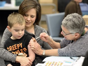 Registered nurse Shannon Ziffle gives a flu shot to five-year-old Evan Habicht as his mother Kyla holds on tight.  October 31 was the first day of flu clinics in Saskatchewan.