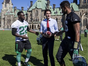 The Saskatchewan Roughriders practised on Parliament Hill in Ottawa on Tuesday October 11, 2016. Prime Minister Justin Trudeau talks with quarterback Brandon Bridge (R) and running back Greg Morris.