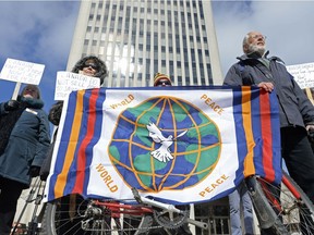 A group of protestors hold a flag during a peace rally at City Hall in Regina on March 19, 2016. Speakers addressed concerns about Canada's sale of weapons to Saudi Arabia and its involvement in the Syrian conflict.