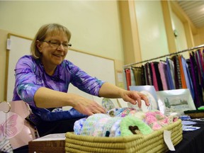 Carol Storie arranges some knit baby hats during the Indoor Cathedral Village Arts Festival Holiday Craft Market at Westminster United Church in Regina, Sask. on Saturday Nov. 19, 2016.
