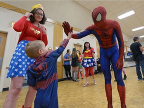 Jessica Redler, left, looks on as her son Toby high-fives Spiderman (Adam Skoretz) during the Saskatchewan Down Syndrome Society's second annual Superhero for a day held at the Italian Club in Regina, Sask. on Saturday Nov. 5, 2016.