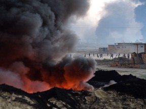Children play football next to an oil field that was set on fire by retreating ISIS soldiers on Oct. 21 in Qayyarah, Iraq.