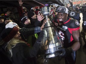 Ottawa Redblacks defensive lineman Moton Hopkins (95) shares the Grey Cup with fans after defeating the Calgary Stampeders in the 104th CFL Grey Cup Sunday, November 27, 2016 in Toronto.