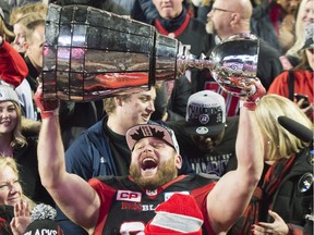 Defensive lineman Zack Evans lifts the Grey Cup after the Ottawa Redblacks' 39-33 overtime victory over the Calgary Stampeders.