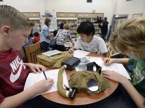 REGINA,Sk: NOVEMBER 8, 2016 -- (L-R) Jaxson Lenz, Fidel Prudent and Jackson Gair examine a WW1 gas mask and complete workbooks. On Tuesday, Grade 5 students at St Marguerite Bourgeoys School got to look at a Supply Line First World War Discovery Box, which the school received from the Canadian War Museum in Ottawa.