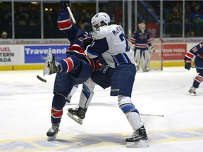 Regina Pats forward Rykr Cole is dumped to the ice by Saskatoon Blades forward Lukus MacKenzie during WHL action at the Brandt Centre on Saturday.