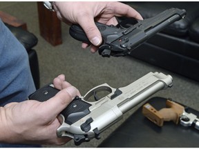A Wascana Pistol club member holds up the real and air gun version of a Beretta 92 FS. The black gun is the real firearm and the silver is the air gun.