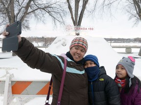 Rina Penas and her family take a photo in front of an ice-sign during New Year's Eve kick-off celebrations for Canada's 150th birthday in Wascana Centre in Regina, Sask. on Saturday Dec. 31, 2016.