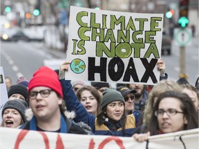 A woman holds a sign reading "Climate change is not a hoax" as demonstrators march during a protest against incoming U.S. President Donald Trump in Montreal on Friday, Jan. 20, 2017.