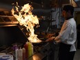 Head chef Vinu Paily makes flames as water hits hot oil at Tamarind restaurant in Regina.