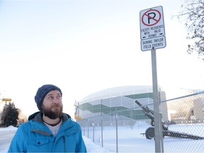 Michael Parker, executive director of the North Central Community Association, looks up at a parking sign near Mosaic Stadium. The NCCA is encouraging residents to attend a meeting Tuesday for residents to voice concerns about the removal of permitted parking only in the area during major stadium events.