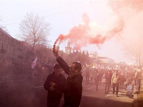 Protesters burn flares and carry Georgian flags during a march in support of Rustavi 2 TV channel in Tbilisi, Georgia, Sunday, Freb. 19, 2017. Hundreds of people marched in central Tbilisi to express their support to independent TV channel Rustavi 2 and blamed the government for an attempt to silence opposition media. (AP Photo/Shakh Aivazov)