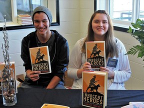 Elias McNab and Maddy Gordon hold copies of Sigmund Brouwer's new book, Innocent Heroes, at Punnichy Community High School.