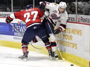 The Lethbridge Hurricanes' Brennan Menall, left, ties up the Regina Pats' Austin Wagner along the boards Tuesday at the Brandt Centre.