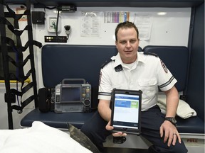 Chris Fay, advanced care paramedic, holds up an iPad with an app that allows paramedics to access patient information.