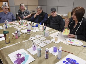 Gwen Friedrich, right, executive director of The Caring Place, explains the piece of art she made during a staff art class at The Caring Place in Regina.