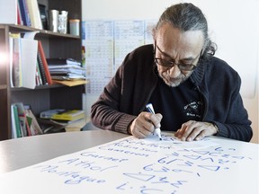 Solomon Ratt, a Cree linguist at First Nations University of Canada, writes out some Cree syllabics in his office in Regina. Ratt would like to see street signs in North Central changed to include Cree syllabics.