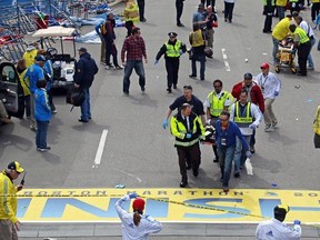 FILE - In this April 15, 2013 file photo, medical workers wheel injured victims across the finish line after a nearby bombing during the Boston Marathon in Boston. The world premiere of &ampquot;Finish Line,&ampquot; a documentary stage play about the bombing, is set to open on Wednesday, March 15, 2017, in Boston. (AP Photo/Charles Krupa, File)
