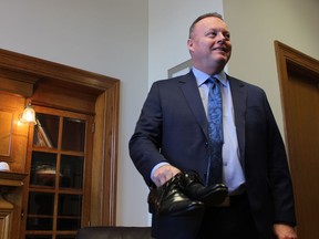 Saskatchewan Finance Minister Kevin Doherty stands with his re-soled shoes to symbolize the government's intention to meet the financial challenges in the 2017-18 budget.