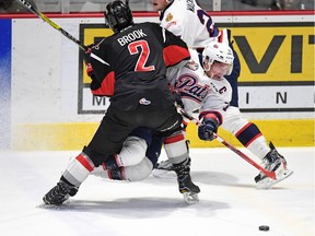 Regina Pats captain Adam Brooks takes a hit to make a play as he's knocked down by Moose Jaw Warriors defenceman Josh Brook during WHL action at the Brandt Centre on Friday.