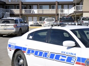 A pair of uniformed Regina Police Service members stand near an open door on the second level of the Sunrise Motel in Regina.