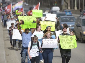 People chant and hold signs during a march organized by Students Mobilizing Against Cuts.