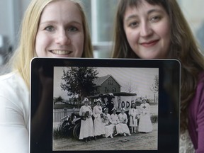 Jacqueline Wagner, left, and Kiera Mitchell, right, show a 1916 photo of Red Cross Committee members. The history students are part of a Regina Public Library presentation on women and the First World War.