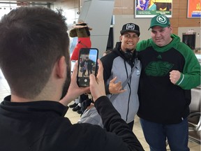 Saskatchewan Roughriders receiver/returner Chad Owens, wearing a black cap, poses for a picture after arriving at Regina International Airport on Monday.