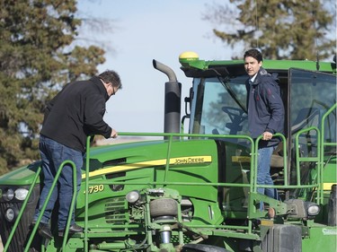 Prime Minister Justin Trudeau, right, and Todd Lewis, left, step off a sprayer at the Lewis Family Farm.