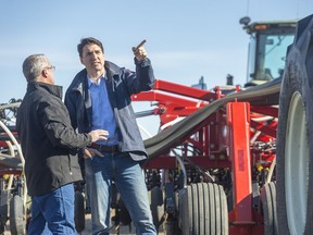 Rod Lewis, left, shows Prime Minister Justin Trudeau around his air seeder at the Lewis family farm.