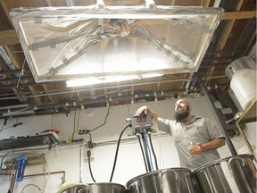 Ale and Lager Enthusiasts of Saskatchewan co-president Kevin Federko looks up at the range hood of an electric brewing system in an ALES member's basement.
