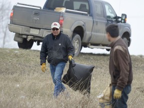 Kamao Cappo, center, and his son Haydar gather trash along the ditch on Highway 46.