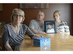 Patti Schlechter, left, holds an ambience box while her husband Joe and daughter Angie hold a photo of Ryan Schlechter, who took his life last June. Patti's friend made her the box to keep mementos of her son Ryan.