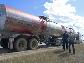 A Regina Police Service member and the driver of a tanker truck walk on the Ring Road near the Wascana Parkway after the truck spilled pig's blood on the highway. The driver braked hard to avoid a collision with another vehicle, and the pressure burst the tanker's lids, spilling blood onto the road. Pig's blood can be rendered and used in a number of products including animal feed.